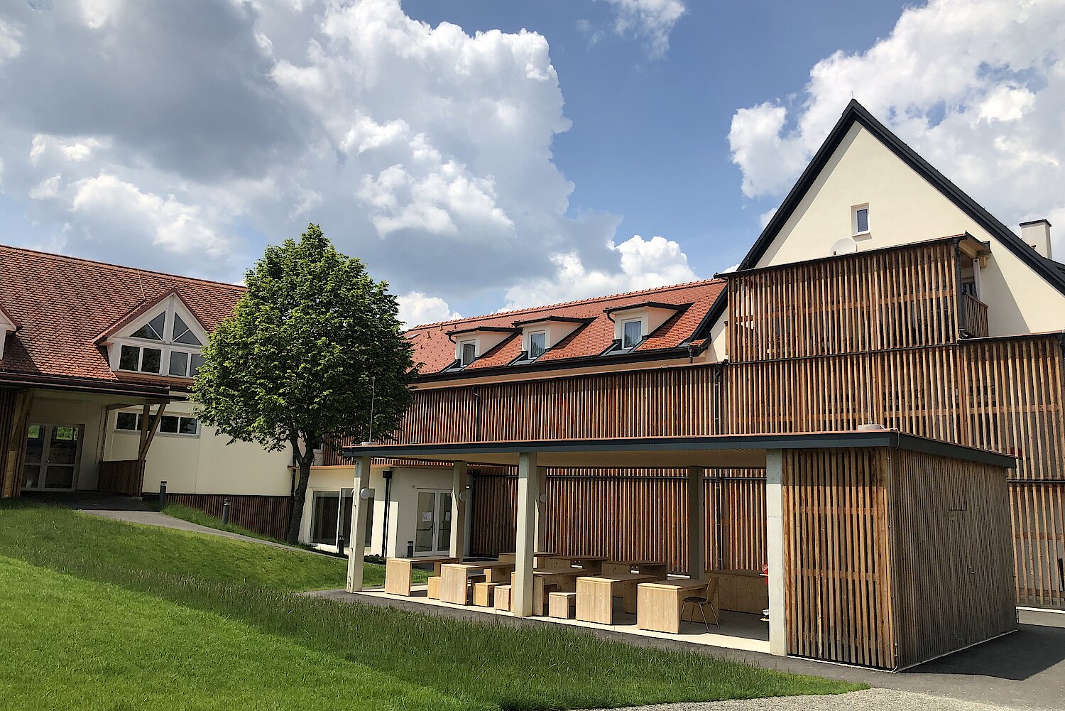 Die frisch sanierte Volksschule Pirching am Traubenberg mit Sonnenschutz aus Holz und einer Freiluftklasse.