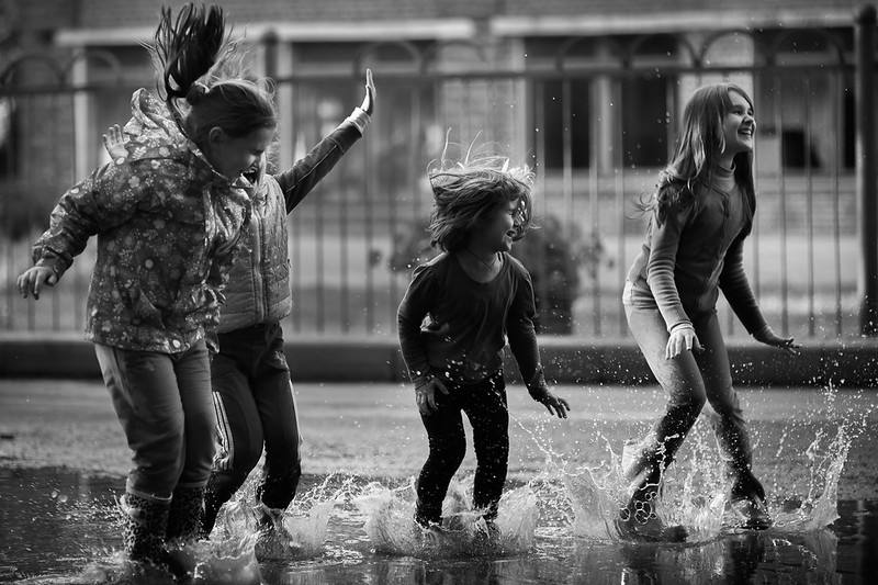 Kinder spielen in einer Wasserlacke.