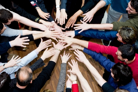 Menschen im Kreis legen Hände sternförmig zusammen.